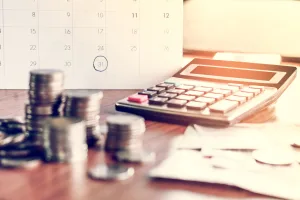 Koncepcja sezonu windykacji długów i rozliczeń podatkowych z kalendarzem terminów, notatką przypominającą o terminie, monetami, bankami i kalkulatorem na stole